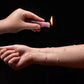 Photo ad of a hand holding a lit candle and dripping wax onto the arm of another person.