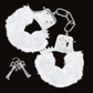 Front facing image of the furry cuffs (white) with the keys next to them.