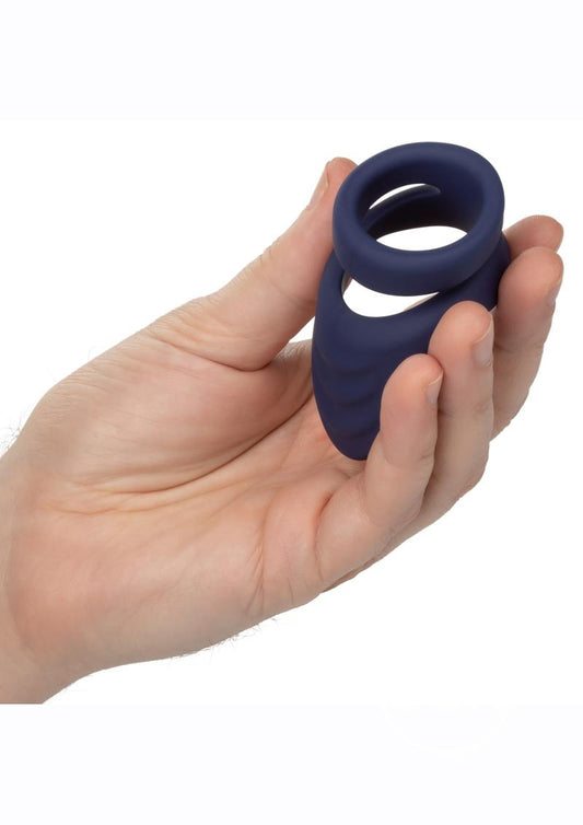 Photo of a hand holding the Viceroy Perineum Dual Cock Ring from CalExotics (blue) to show its size by comparison.