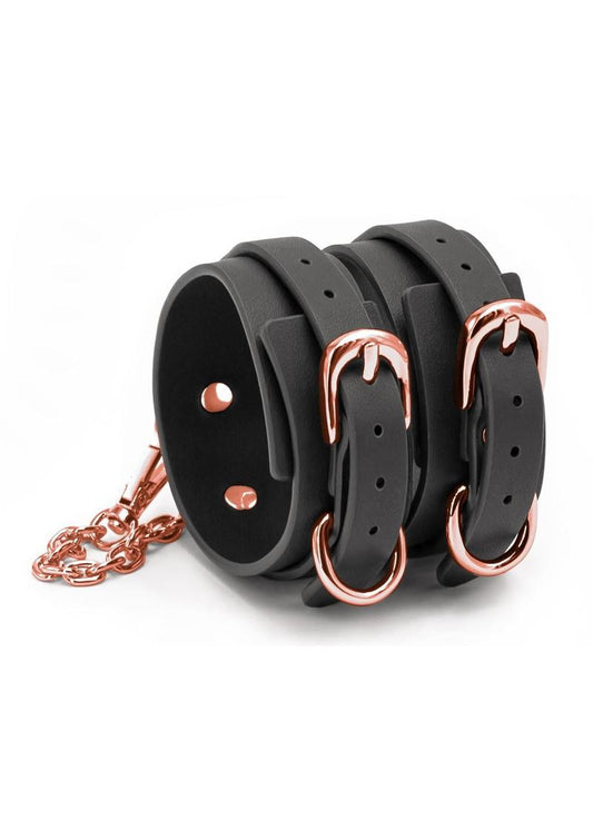 Side angle view of the Bondage Couture Ankle Cuffs (black) from NS Novelties, shows off the sleek look of the cuffs with its rose gold hardware.