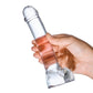 Photo of a hand holding the glass dildo showing its lifelike head and testicles.