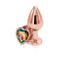 Close-up photo shows the Rear Assets Heart Anal Plug w/ Gem (rose gold/rainbow) from NS Novelties, shows its long neck for comfort as well as its faceted heart-shaped gem.