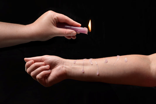 Photo ad of a hand holding a lit candle and dripping wax onto the arm of another person.