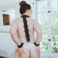 Photo ad of the back of a woman with her arms behind her wearing the restraints.