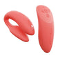 We-Vibe Chorus (coral) top angle view showing the unique curved shape of the wearable couples' vibe and its ribbed G-spot stimulator. Pictured next to it is the remote.