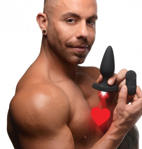 Man holding the plug with the red laser heart shining. He is also holding the remote. 