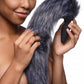 Photo of a woman holding the long gray fox tail with anal plug base attachment in her hand.