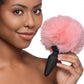 Photo of the woman holding the pink fluffy bunny tail attached to the anal plug base.