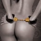 Ad for the Fetish Fantasy Gold Deluxe Furry Cuffs from Pipedreams (black/gold) shows the back of a woman wearing the cuffs.
